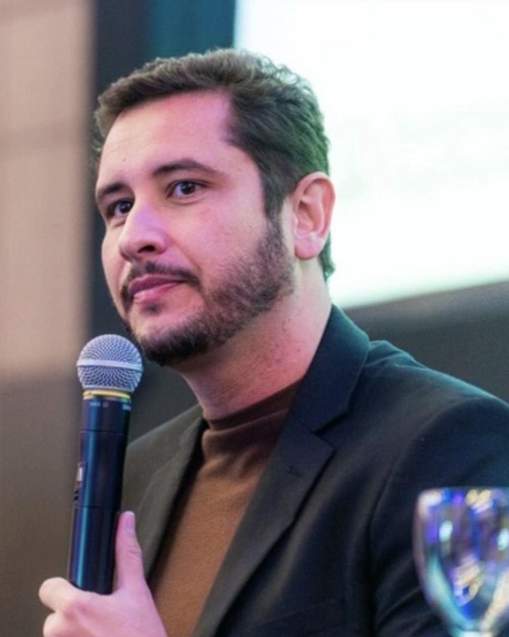 Diego Meloni com o microfone num talk show sobre saúde pública